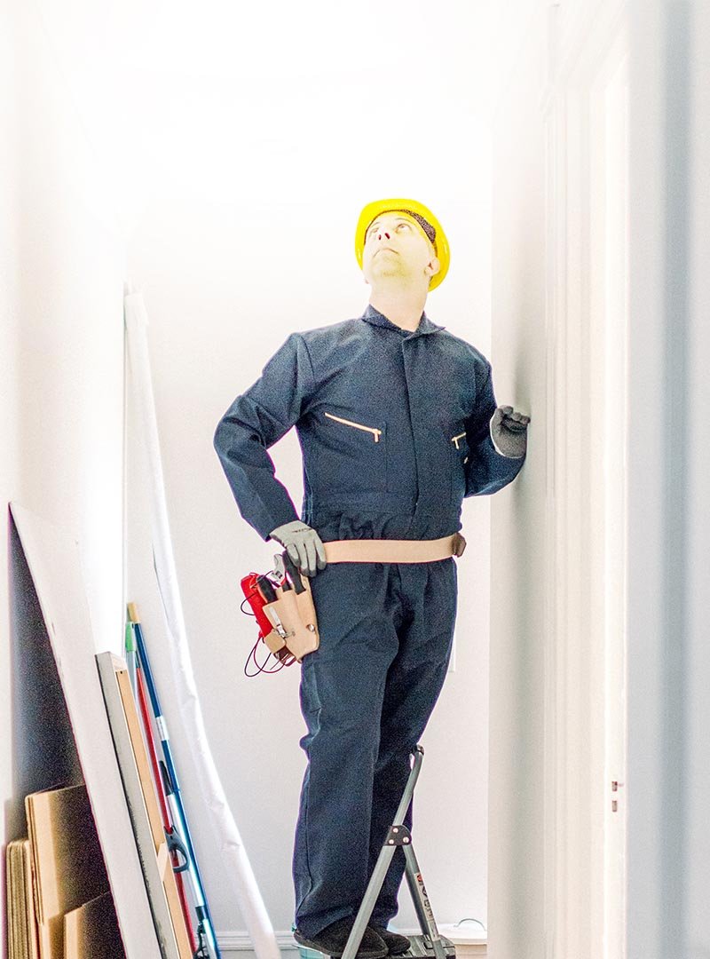 Ouvrier sur un escabeau analysant le plafond